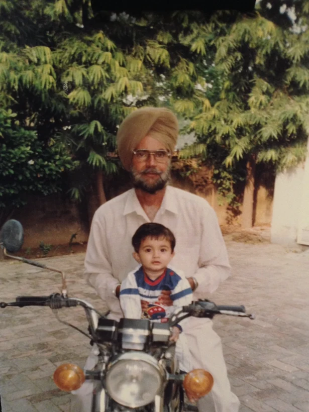 A childhood photograph sitting on a motorcycle with a family member.