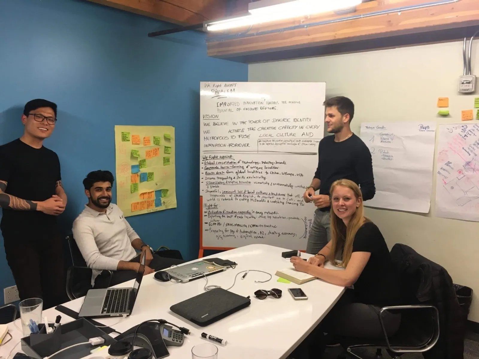 Four people gathered beside a whiteboard.
