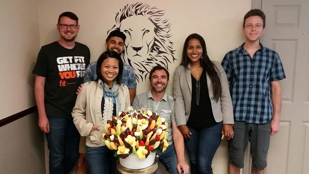 The Booming Group team gathered beside a fruit arrangement and lion mural.