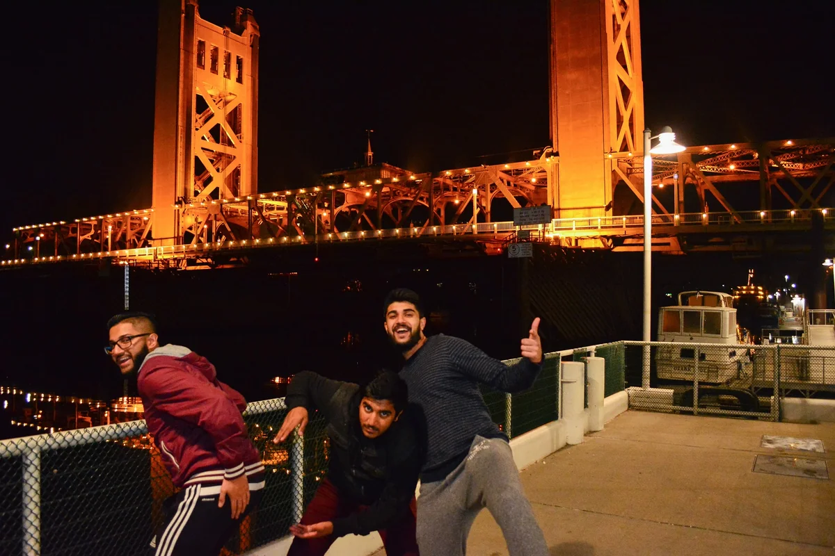 A group beside a brightly lit bridge at night.