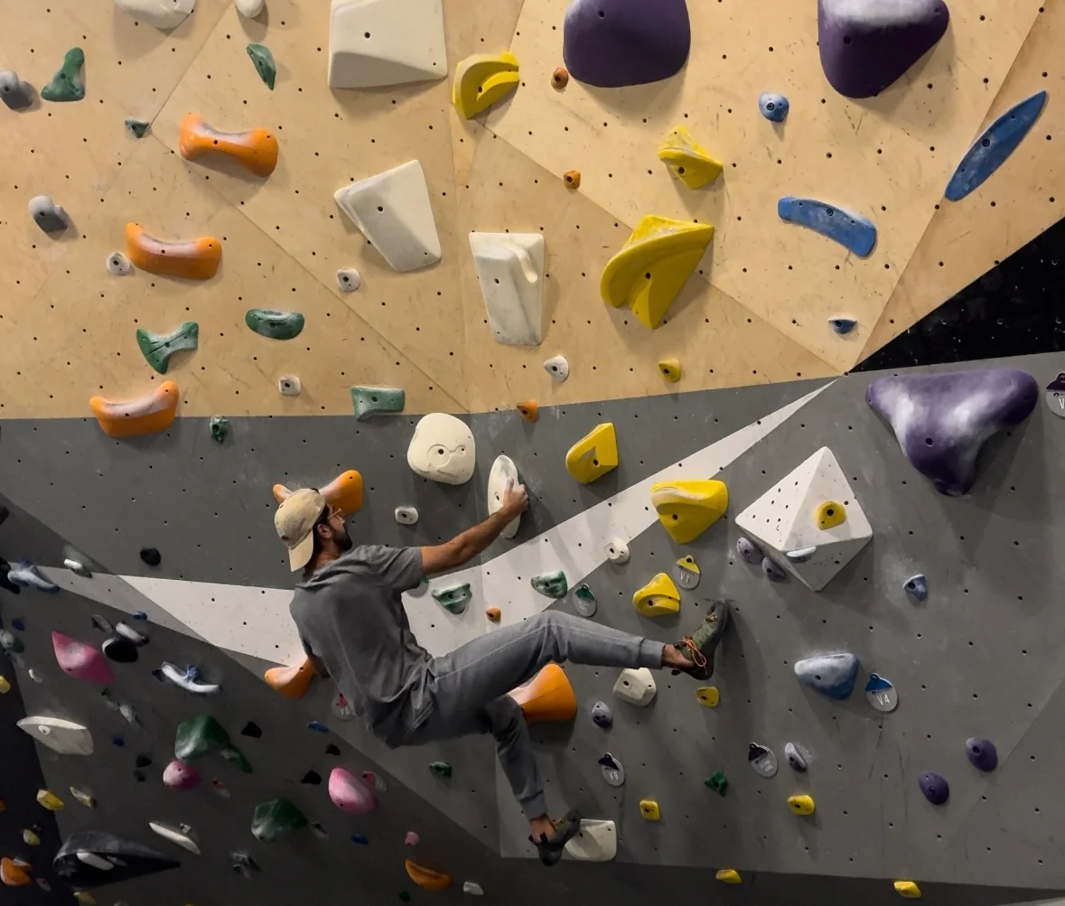 Bouldering on an indoor climbing wall with colorful holds.