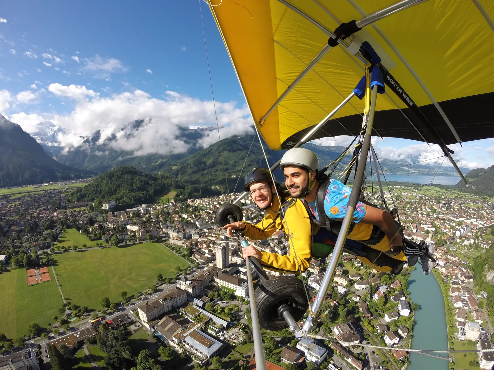 Tandem hang-gliding above a town, river, and mountains.