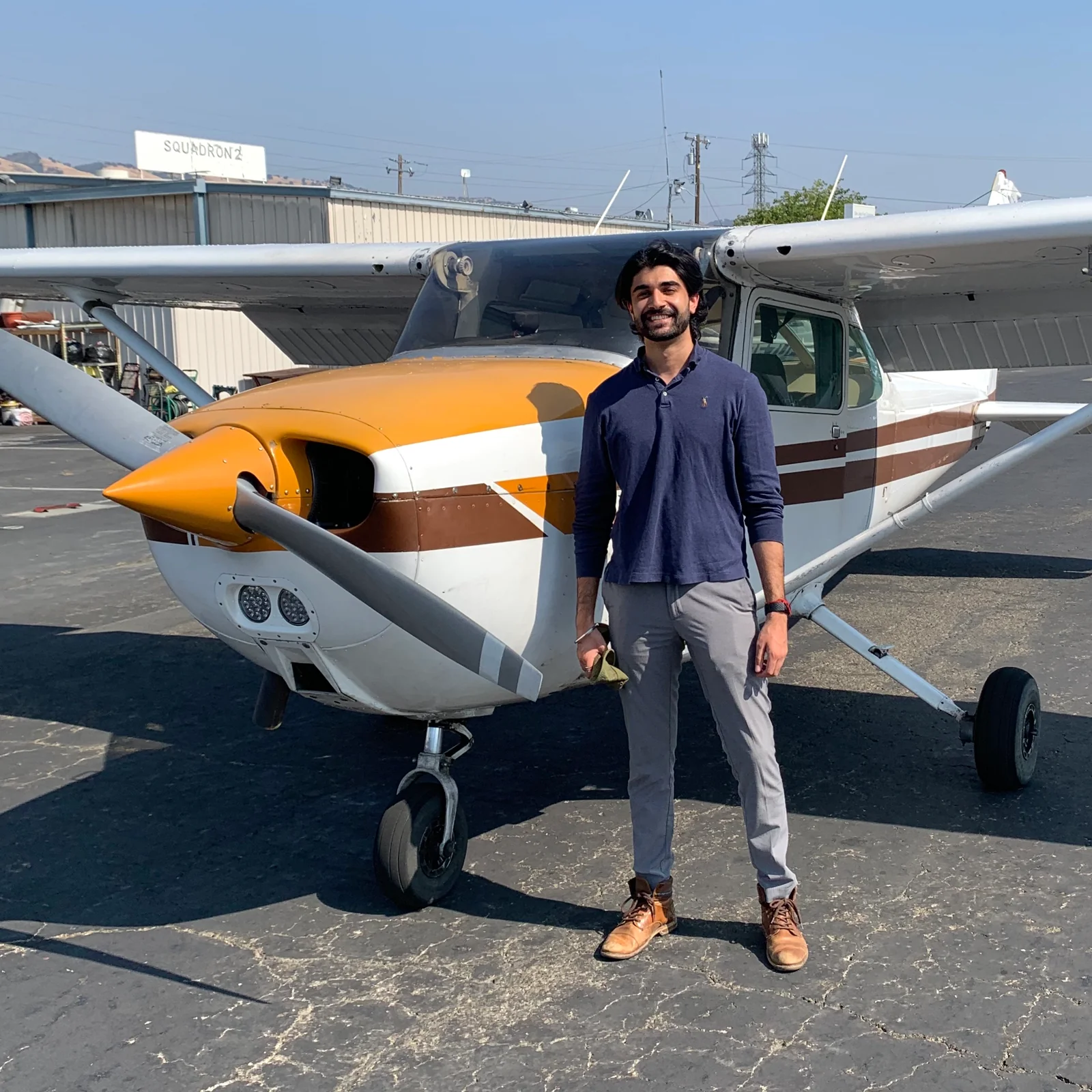Standing beside a yellow, brown, and white airplane on the airfield.