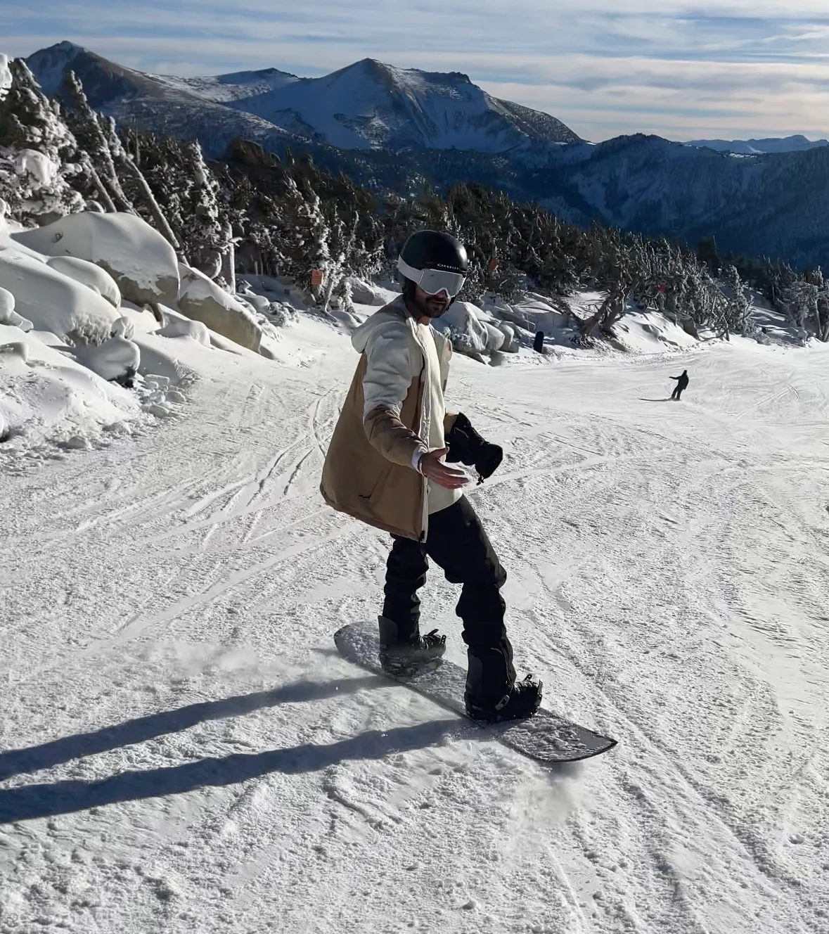 Snowboarding down a slope with snow-covered mountains in the background.