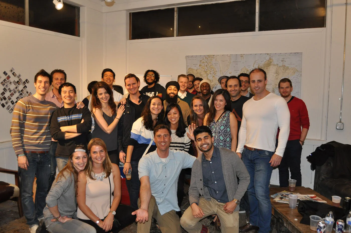 A group gathering at Startuphouse in front of a world map.